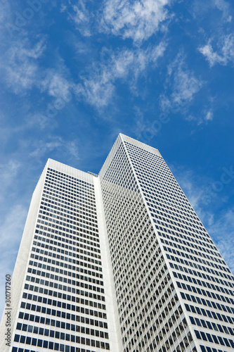 Anonymous white office tower skyscraper standing outdoors in bright blue sky