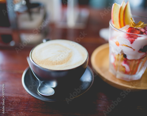 cup of coffee and homemade fruit yoghurt with strawberry jam, apple and conflake photo