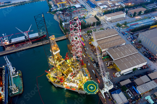 Aerial view of a jack up oil drilling rig and dry dock ship in the shipyard for maintenance during suset time.