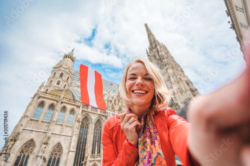 Woman stands on the background of St. Stephen's Cathedral in Vienna with the flag of Austria in hand, Austria