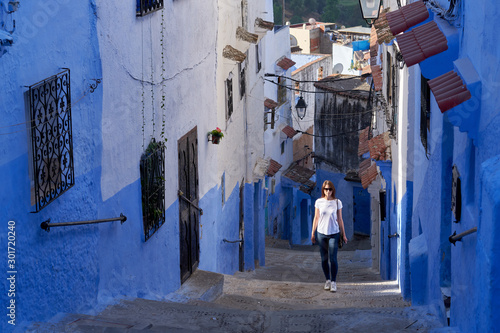 Woman travels through the narrow blue streets of the old Medina in Chefchaouen town in Morocco.  © vadim_ozz