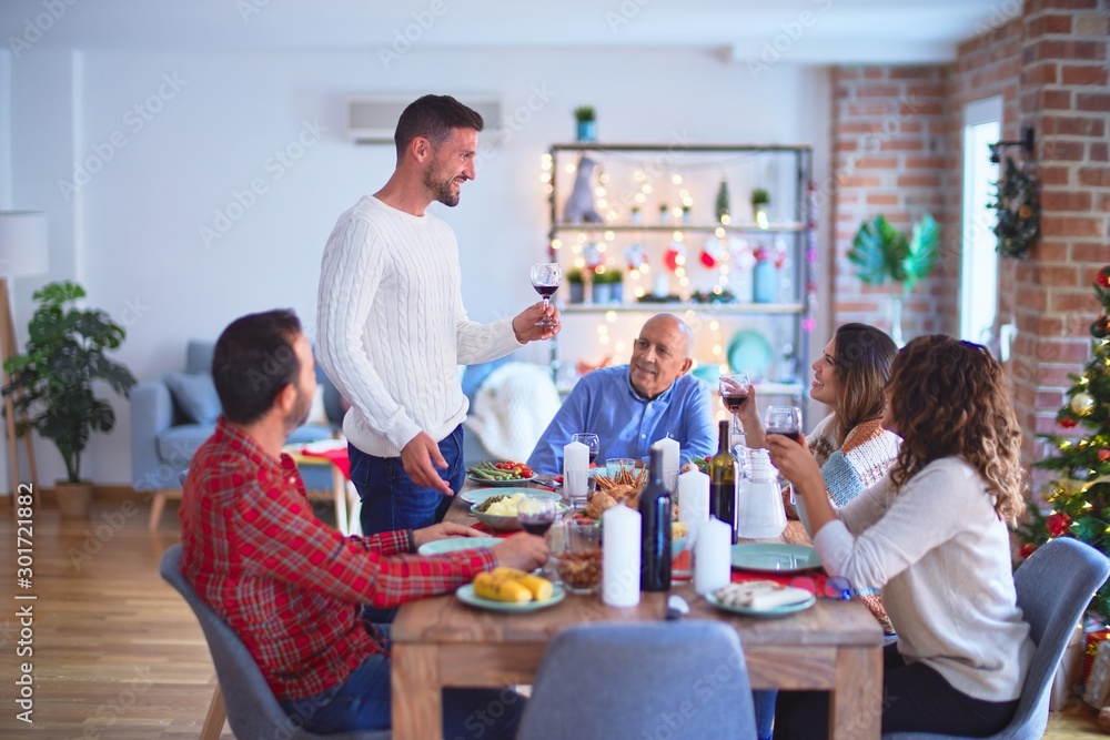 Beautiful family smiling happy and confident. Man speaking a speech celebrating Christmas at home Beautiful family smiling happy and confident. Man speaking a speech celebrating Christmas at home