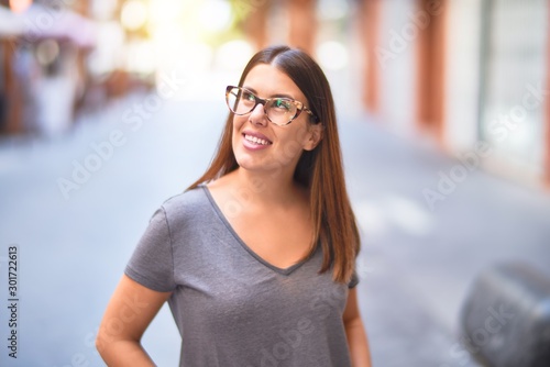 Young beautiful woman smiling happy and confident. Standing with smile on face at town street