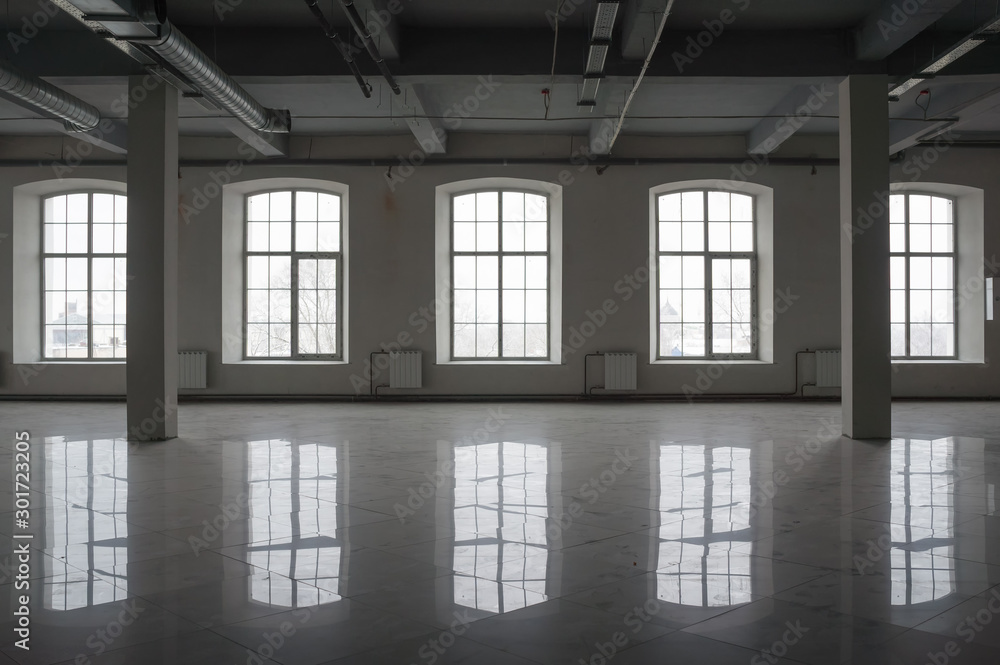 Empty large room in old factory building with row of big windows, columns  and pipes under the beton ceiling. Background or mock up for design in  urban, industrial or loft style Stock