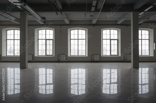 Empty large room in old factory building with row of big windows, columns and pipes under the beton ceiling. Background or mock up for design in urban, industrial or loft style