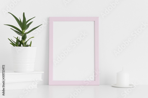 Pink frame mockup with workspace accessories and a aloe vera on a white table.Portrait orientation.