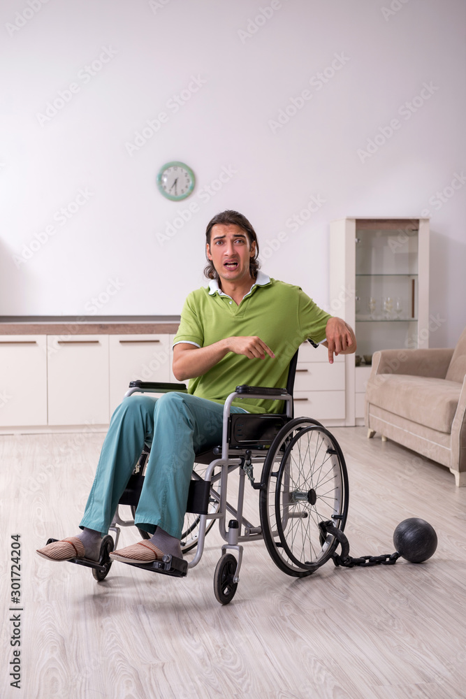 Young male invalid in wheel-chair suffering at home Young male invalid in wheel-chair suffering at home