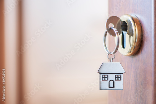 Home key with house keyring in the door keyhole photo