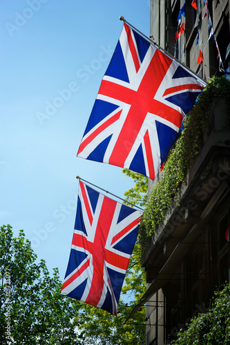 Union Jack flags hanging above the leafy streets of London, UK against bright blue sky