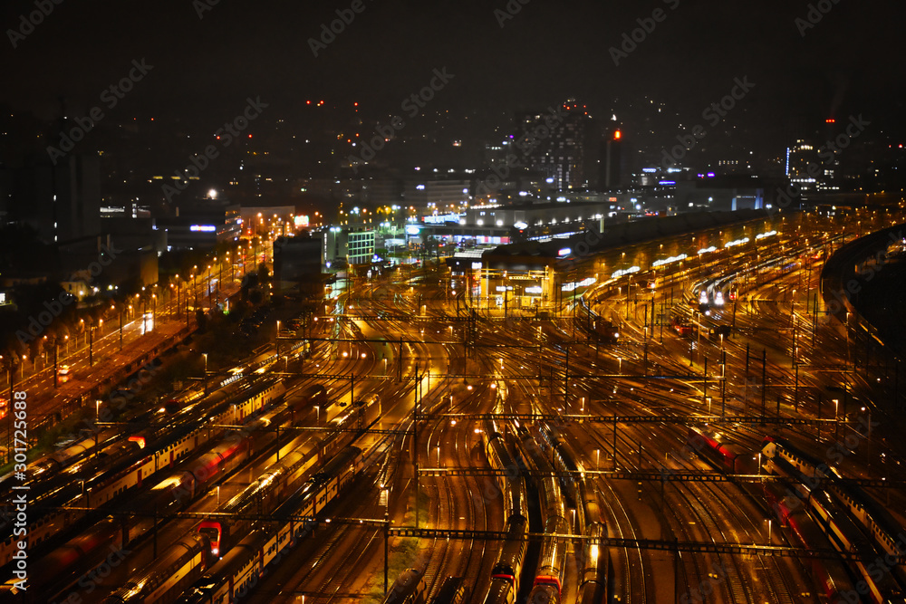 Aerial view of freight, cargo and passenger trains waiting at the train station parking lot during the night
