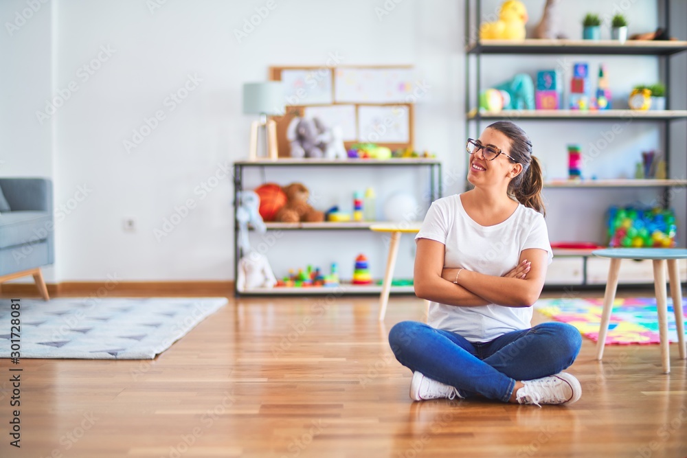Young beautiful teacher wearing glasses sitting at kindergarten Young beautiful teacher wearing glasses sitting at kindergarten