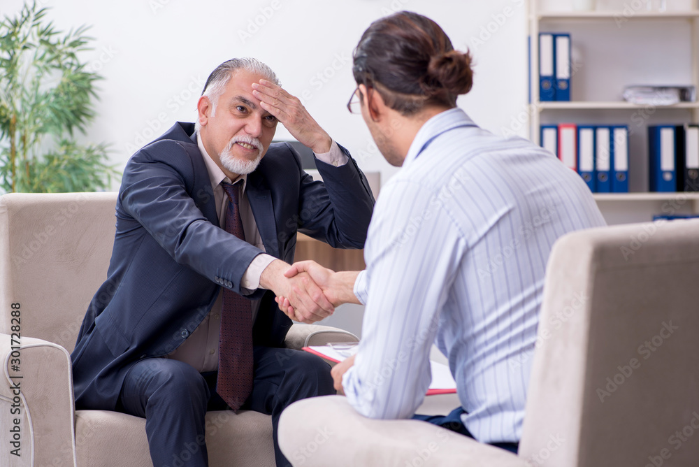 Old man visiting young male doctor psychologist Old man visiting young male doctor psychologist