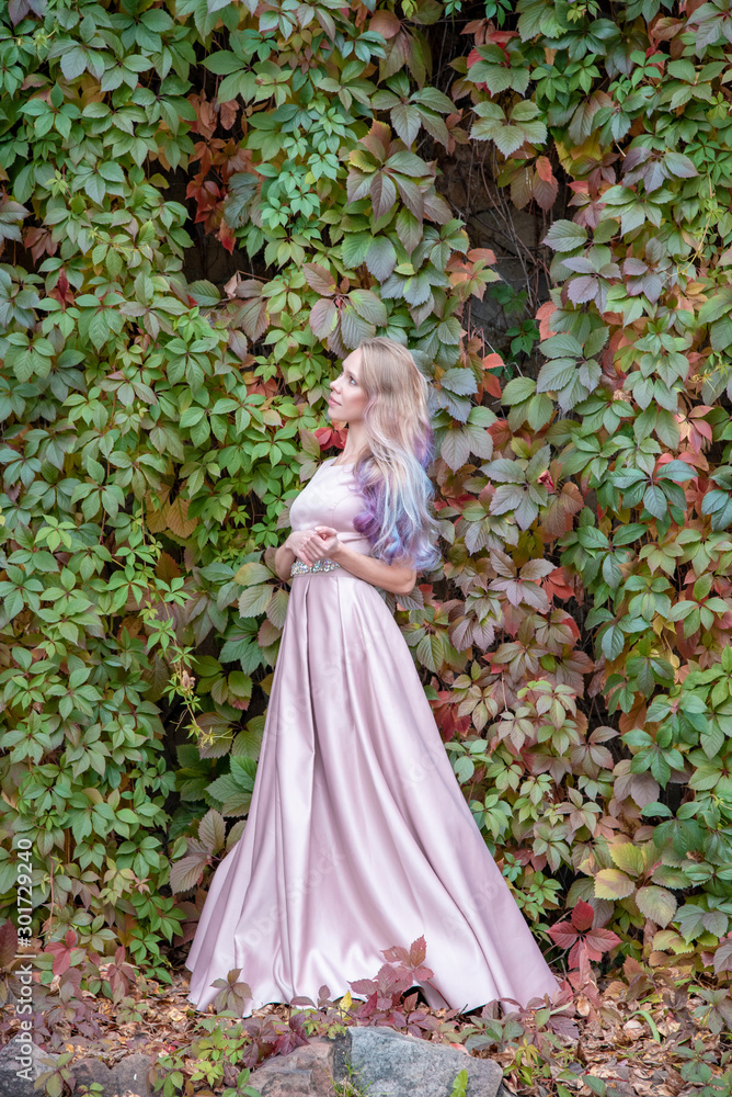 Beautiful blonde girl with long hair in a dress posing on a background of autumn foliage Beautiful blonde girl with long hair in a dress posing on a background of autumn foliage