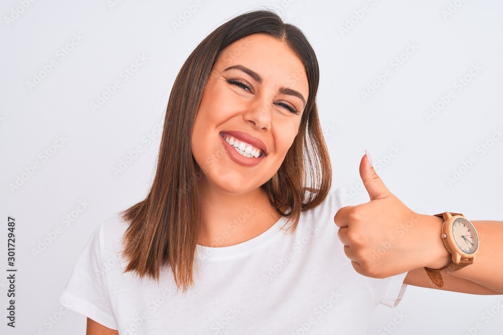 Close up of beautiful and young brunette woman standing over isolated white background happy with big smile doing ok sign, thumb up with fingers, excellent sign Close up of beautiful and young brunette woman standing over isolated white background happy with big smile doing ok sign, thumb up with fingers, excellent sign