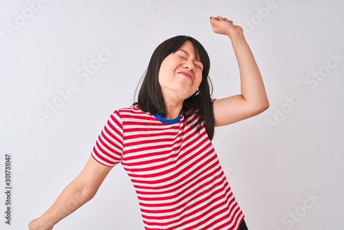 Young beautiful chinese woman wearing red striped t-shirt over isolated white background Dancing happy and cheerful, smiling moving casual and confident listening to music