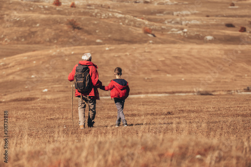 Senior man with grandson on country walk in autumn.