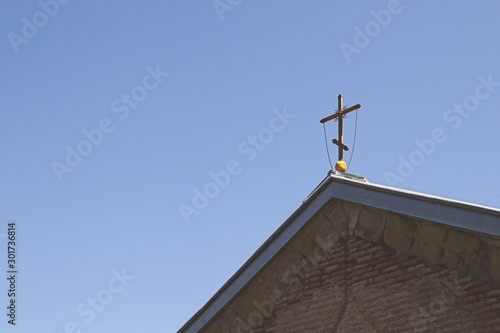 Christianity background image consisting of a cross on a church building with a blue sky background. 