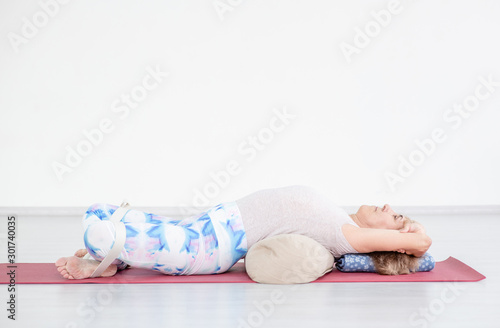 Valokuva Senior woman practicing yoga, lying in Reclined Butterfly exercise