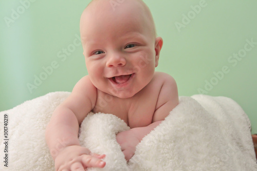 Baby smiles into the camera lens.