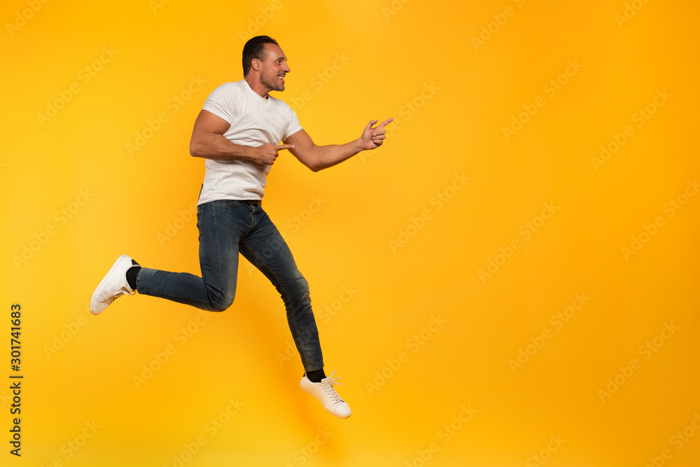 Sport man jumps on a yellow background. Happy and joyful expression.