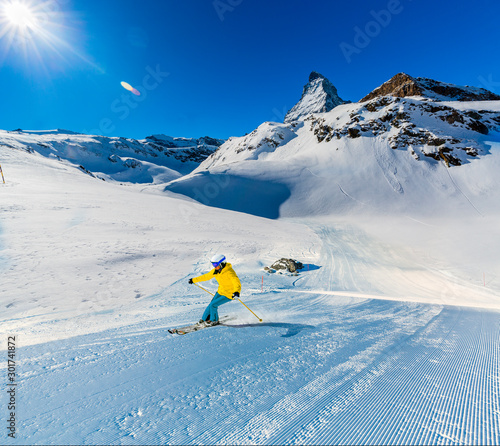Man skiing on fresh powder snow with Matterhorn in background, Zermatt in Swiss Alps.