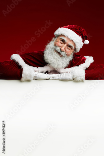 Portrait of classic Santa Claus smiling at camera while posing over blank white sign, copy space © Seventyfour