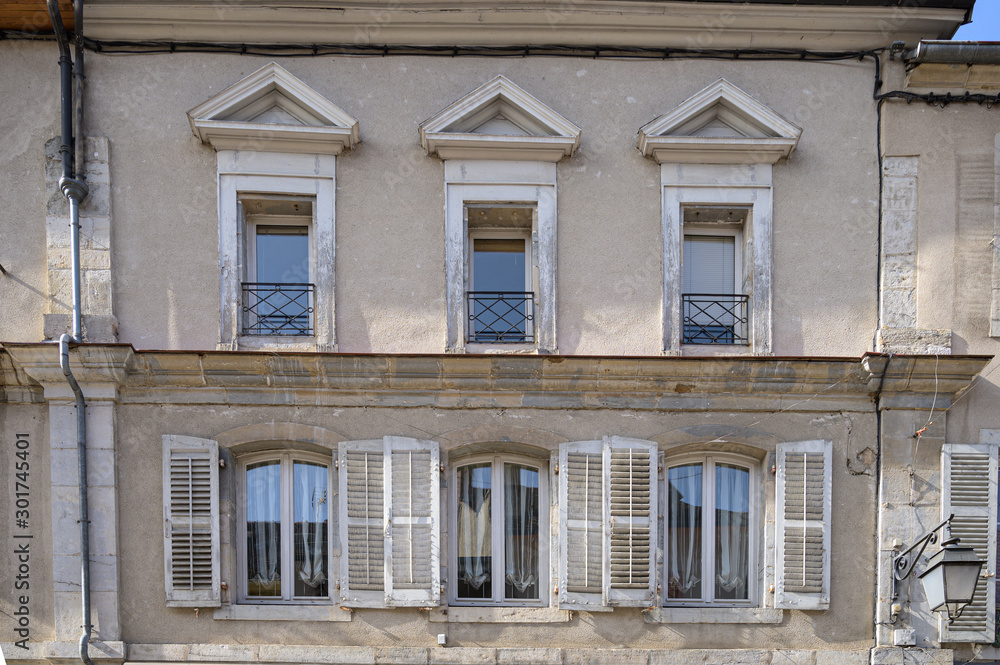 Typical facade of an old apartment above shops in the Frence town of Poligny in the Jura department in Franche-Comté.