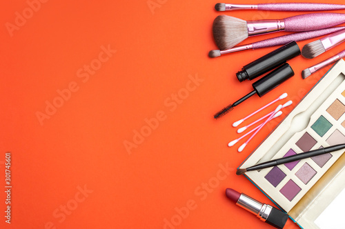 Makeup cosmetics on bright orange background. Top view. Space for text.