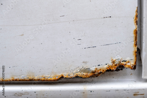 Hard corrosion and rust on the body and doors of the car white.