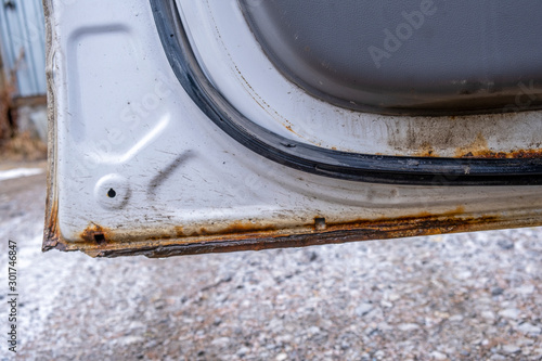 Hard corrosion and rust on the body and doors of the car white.