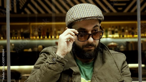 An obvious adult male adult flirter at a cafe checking out women.Stereotype of  European man winking at females passing by,taunting smiling and flirting in an apparent/blatant way.