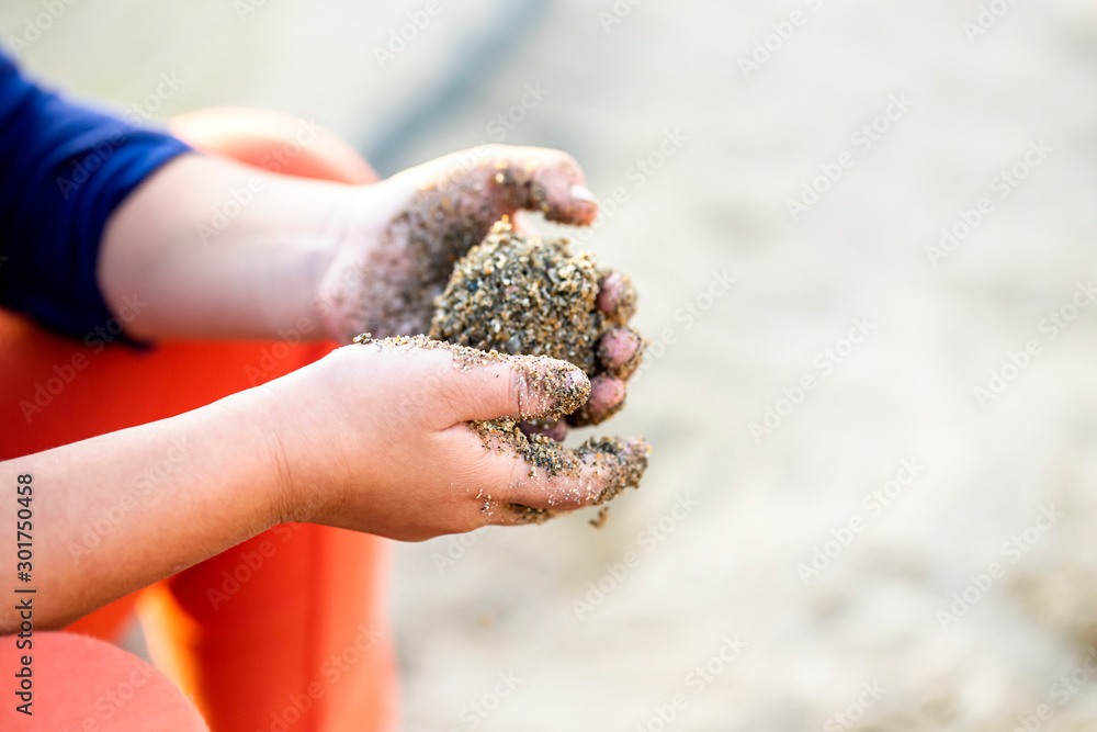 子供が砂で団子を作っている手とコピースペース