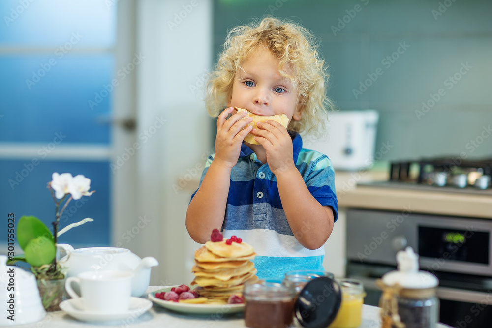 Little curly boy eating sweet pancakes Little curly boy eating sweet pancakes