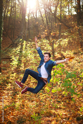 Young funny and curious handsome man jumping in forest park, lifestyle and freedom concept