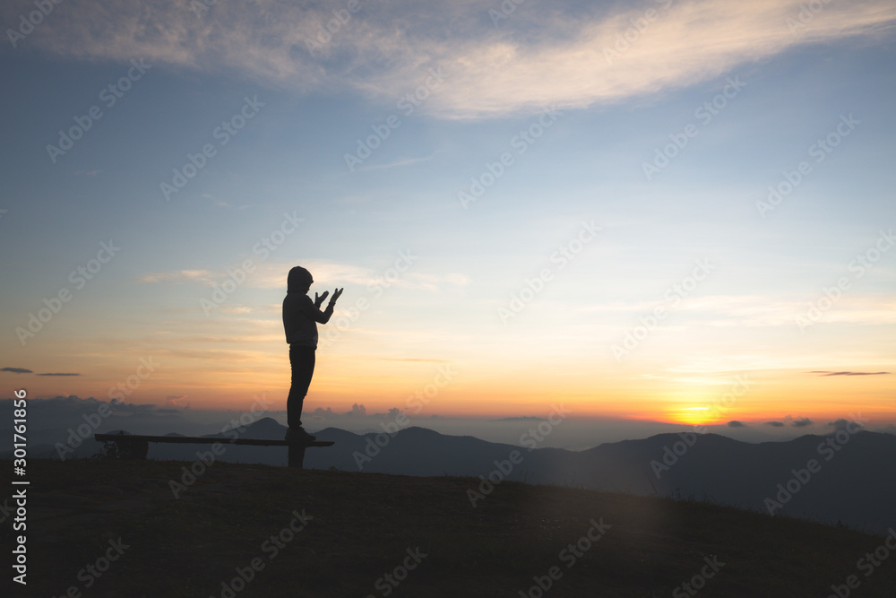 Silhouette of young  human hands  praying to god  at sunrise, Christian Religion concept background.