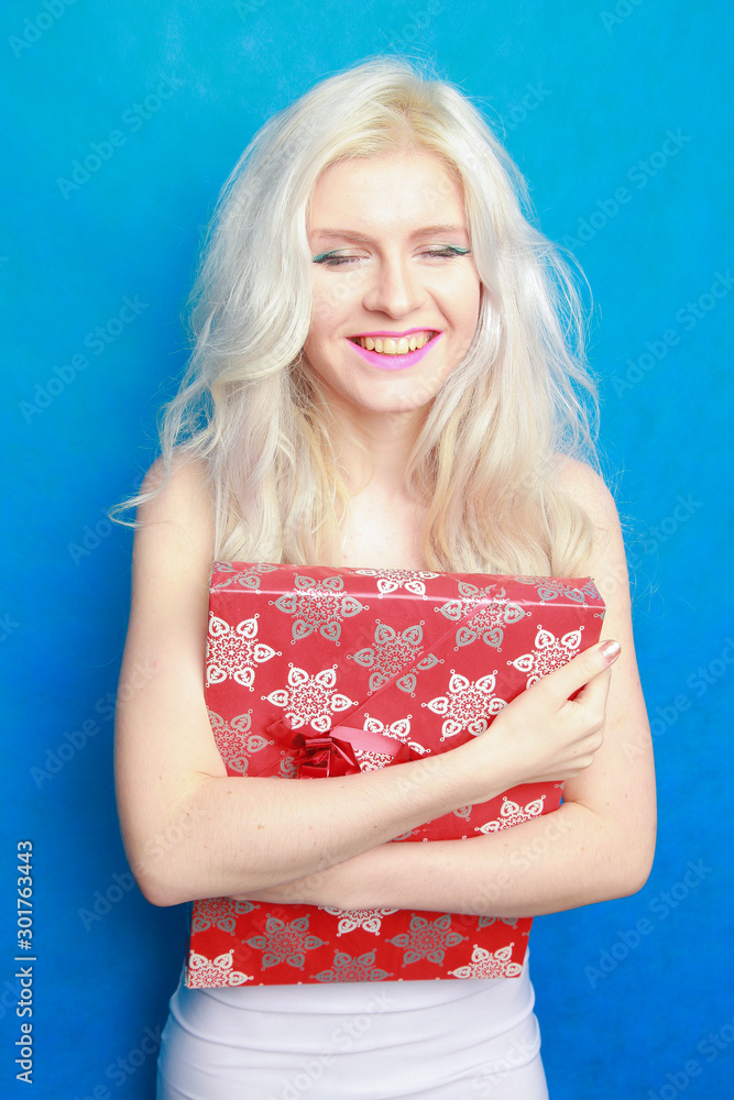 Time for xmas gifts - gift box in hand of beautiful model girl on blue studio background Time for xmas gifts - gift box in hand of beautiful model girl on blue studio background