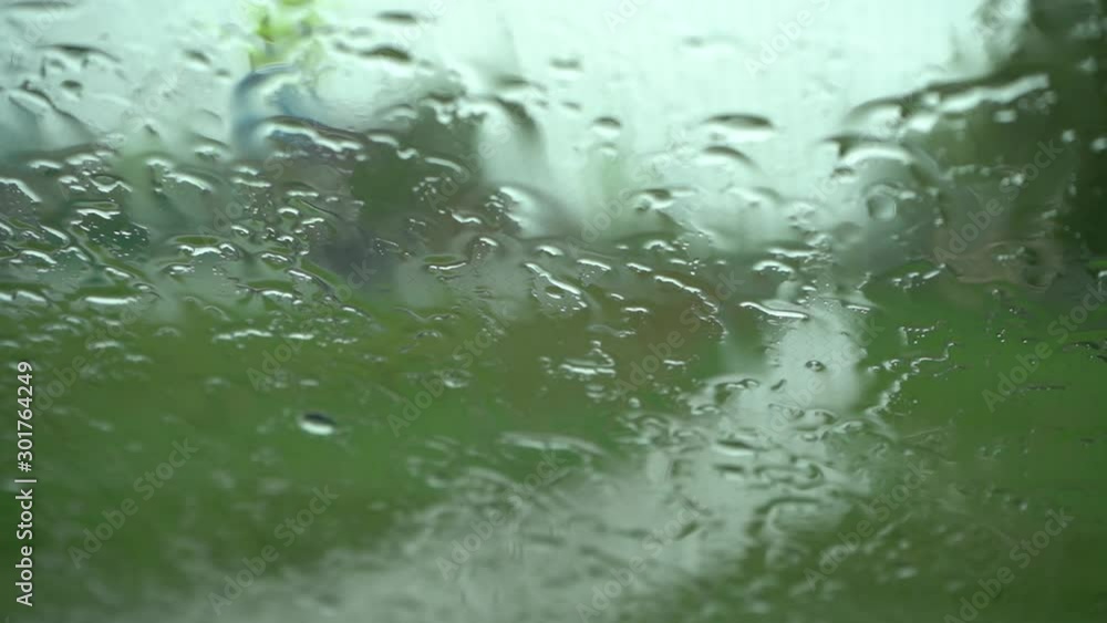 Raindrops on the windshield of a car standing without movement, inside view. Rainy cloudy day. No people. Water flows down the glass. Raindrops on the windshield of a car standing without movement, inside view. Rainy cloudy day. No people. Water flows down the glass.