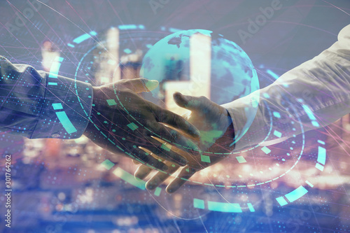 Double exposure of world map on cityscape background with two businessmen handshake. Concept of international business © Andrey