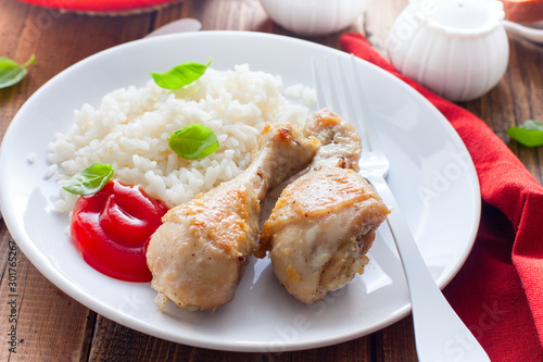 Fried chicken drumsticks with rice on a white plate, selective focus
