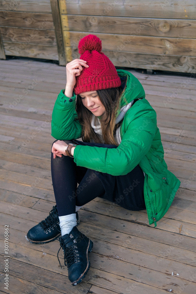 Woman hipster in bright clothes laughing and smiling. Young happy girl in a red knit hat, green jacket, grey scarf, yellow small bag. Women's fashion. Woman hipster in bright clothes laughing and smiling. Young happy girl in a red knit hat, green jacket, grey scarf, yellow small bag. Women's fashion.