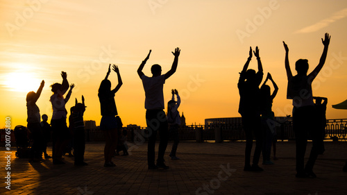 Εκτύπωση καμβά Unrecognizable people silhouette dancing on city festival at sunset