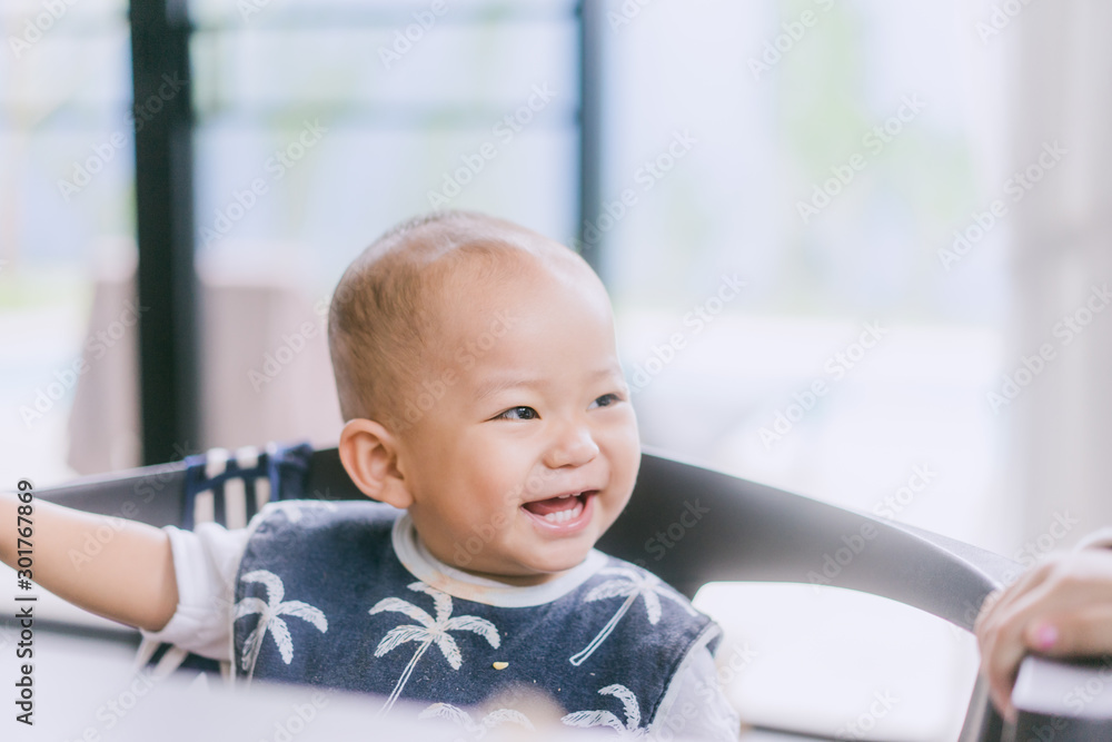 Asian baby boy sitting on dinner table and laughing looking to his sister. Asian baby boy sitting on dinner table and laughing looking to his sister.