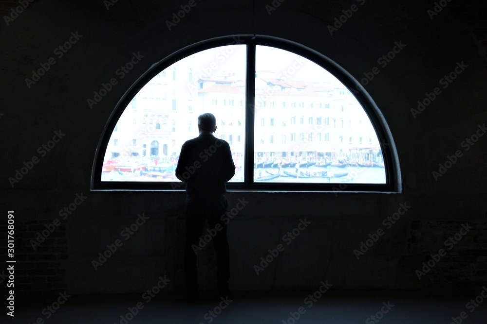 Window inside a building in Venice. Silhouette of a man and play of light and shade. Italy, South Europe.