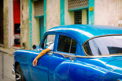 old blue car driving through the central streets of havana , cuba