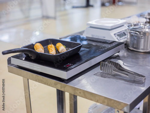 Fototapeta Naklejka Na Ścianę i Meble -  Process of cooking chicken rolls with herbs in frying pan with oil on electric stove at cuisine of restaurant. Professional cooking, catering, cookery, gastronomy and food concept