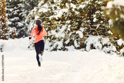 Girl jogging in the snow on the nature in winter.Back view
