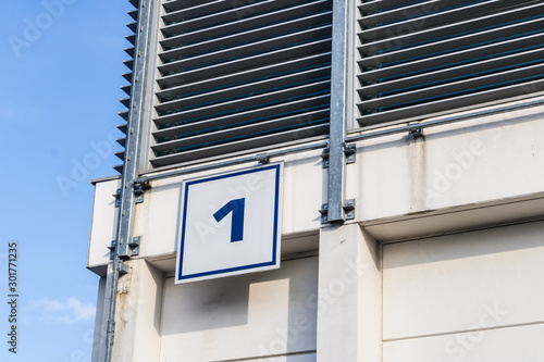 Number one (1) on the business building, big industrial building with number one on the top and a blue sky background - Image
