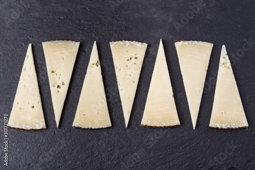 Fotografie Tapa de porciones cortadas en triángulo de queso manchego curado sobre piedra os