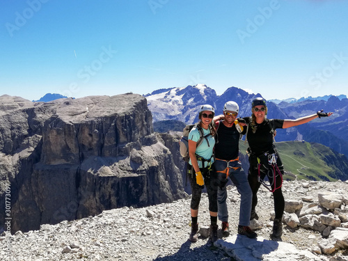 mountain guide and two female climbers celebrate standing on the summit after a climb