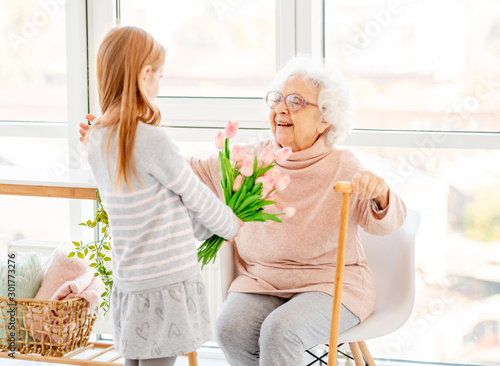 Girl presenting bouquet to old woman